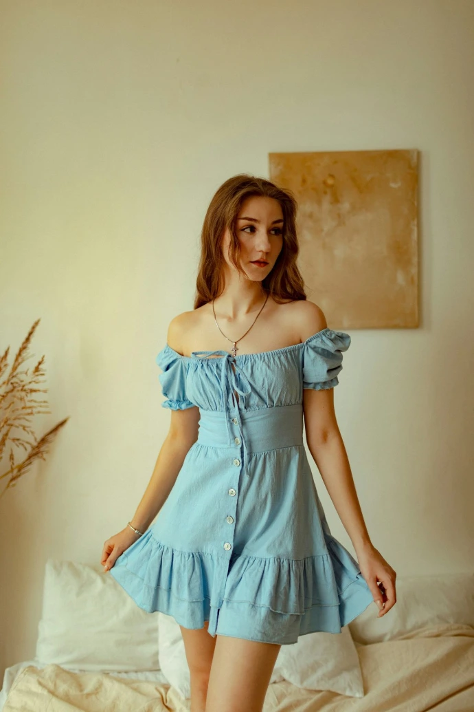 Young woman in a light blue dress standing indoors